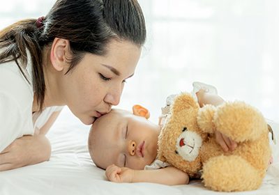 baby-sleeping-with-teddy-bear-mother-kissing-her
